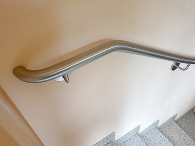 Edelstahl Treppenhandlauf an viertelgewendelter Treppe am oberen Treppenende montiert - normgerechtes Handlaufende - Handlauf zusätzlich 2x gebogen für einen waagerechten Auslauf mit Ende zur Wand