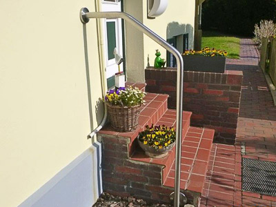 Edelstahl Handlauf freistehend gebogen in der Form 3 - 2 Bögen - an einer Eingangstreppe auf der Nordseeinsel Wangerooge - Befestigung seitlich an der Treppe und an der Hauswand