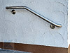 Edelstahl Handlauf an der Eingangstreppe - einmal gebogen, zusätzlich Handlaufenden zur Wand gebogen